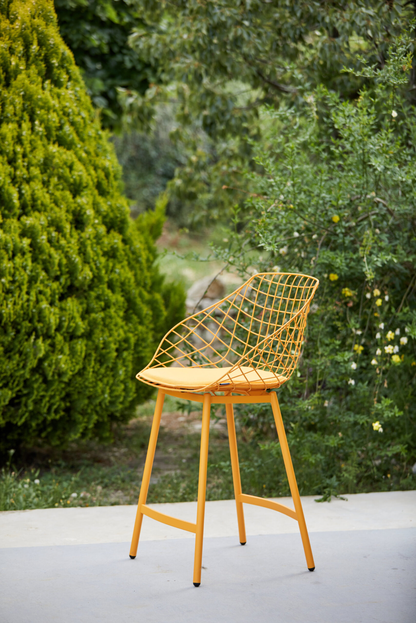 Canasta outdoor chair with woven wire shell in terrace setting