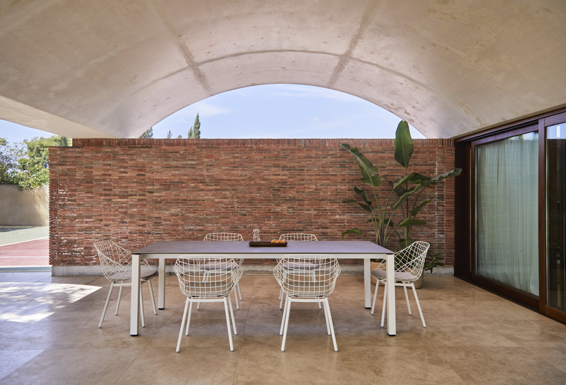 Canasta outdoor chair with woven wire shell in terrace setting