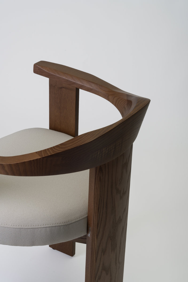 Image of the Nebula chair showcasing its embracing solid wood backrest from a three-quarter angle.