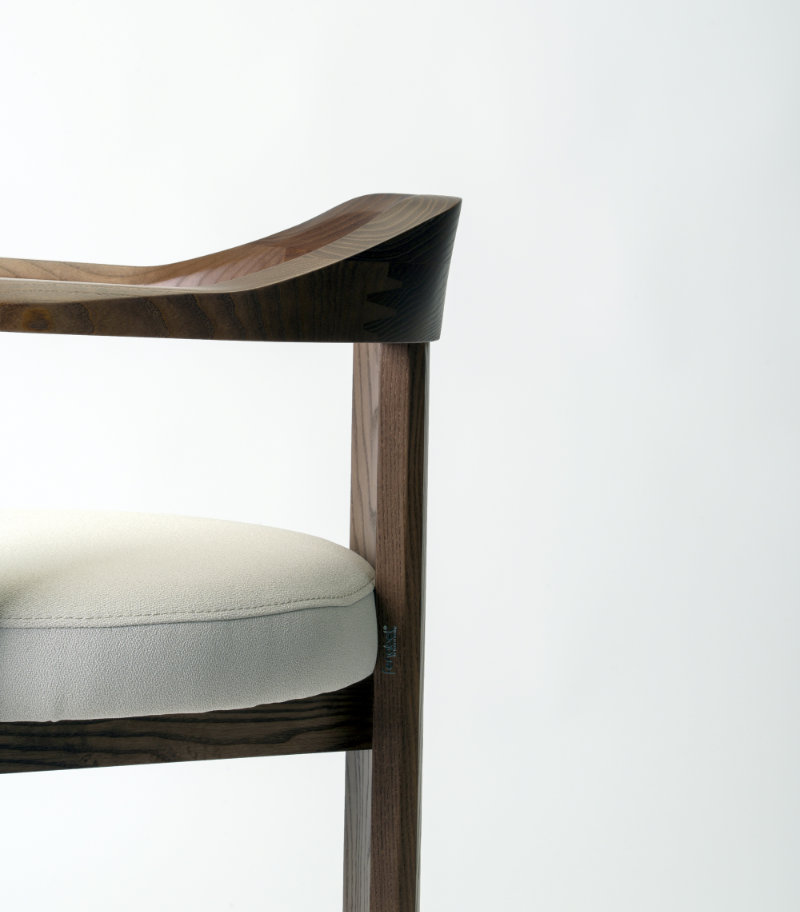 Image of the Nebula chair showcasing its embracing solid wood backrest from a three-quarter angle.