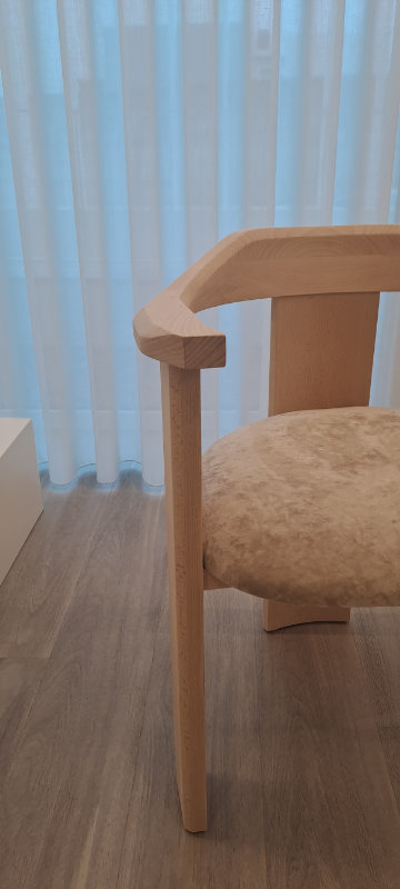 Image of the Nebula chair showcasing its embracing solid wood backrest from a three-quarter angle.