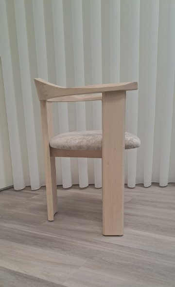 Image of the Nebula chair showcasing its embracing solid wood backrest from a three-quarter angle.