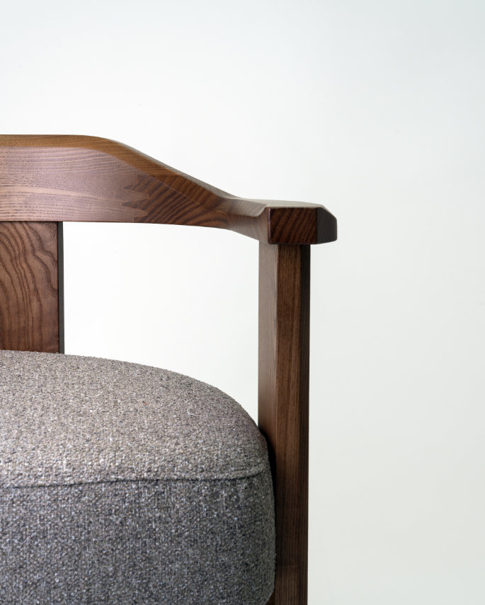 Image of the Nebula chair showcasing its embracing solid wood backrest from a three-quarter angle.