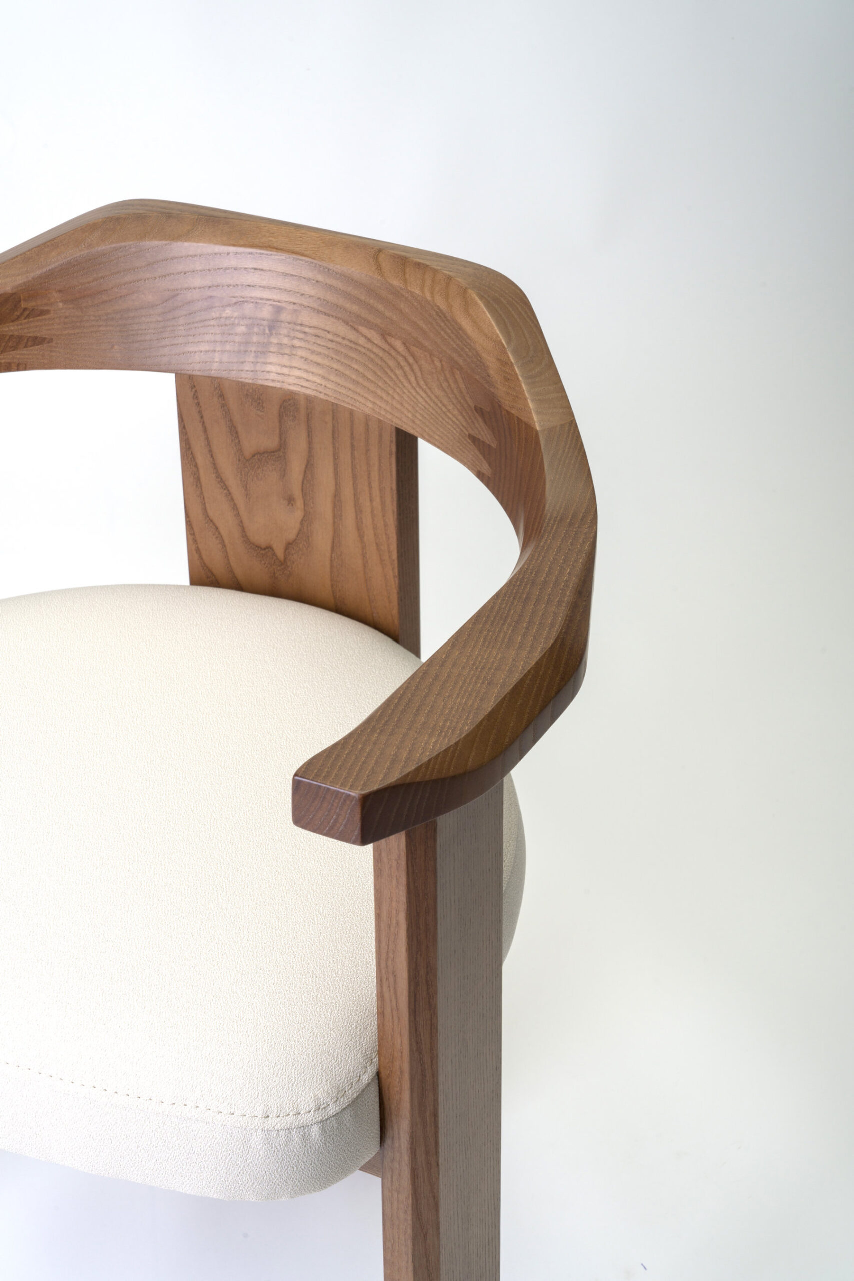 Image of the Nebula chair showcasing its embracing solid wood backrest from a three-quarter angle.