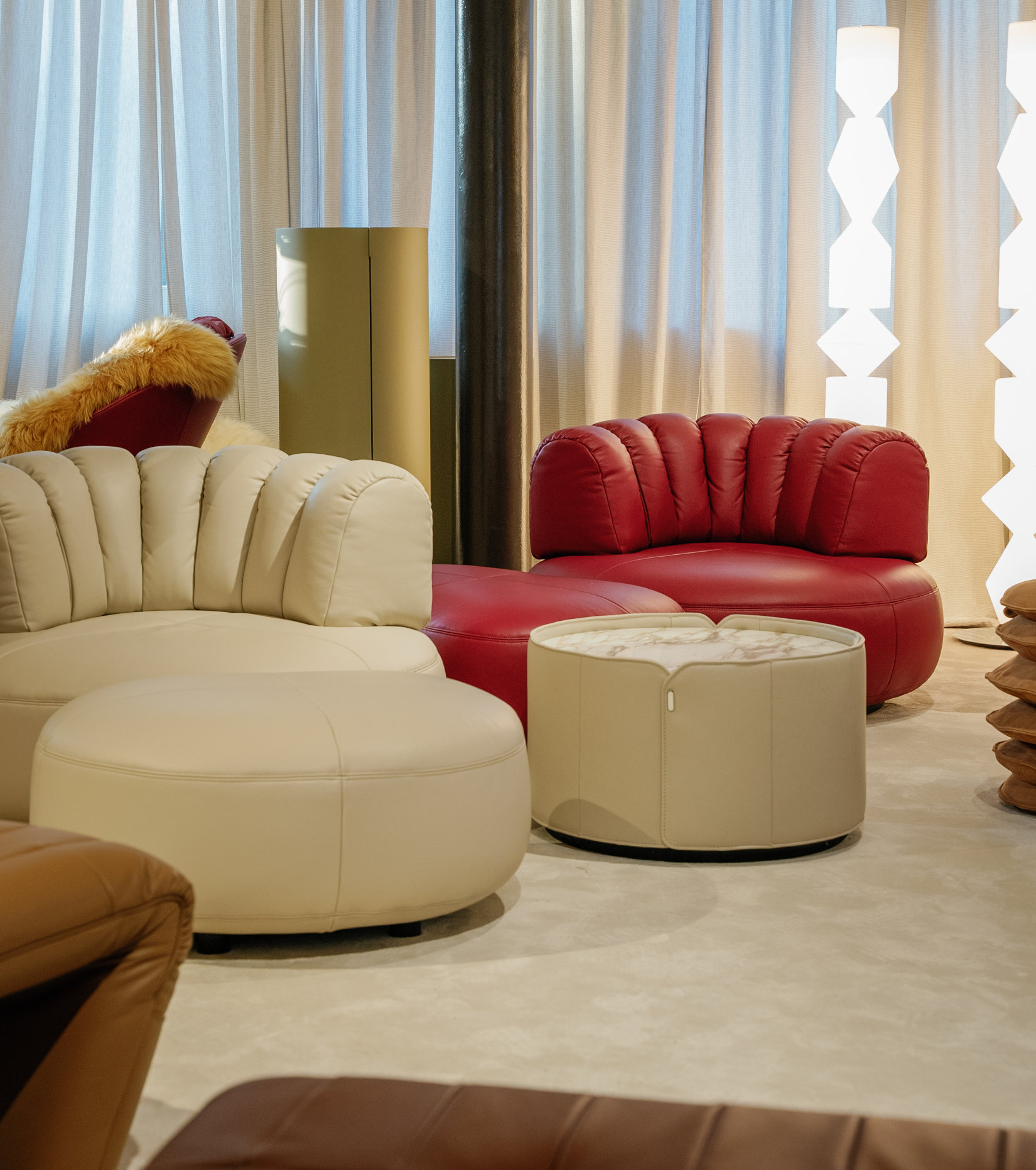 Upholstered lounge chair with circular base and segmented padded backrest, soft sculptural design. during milan design week