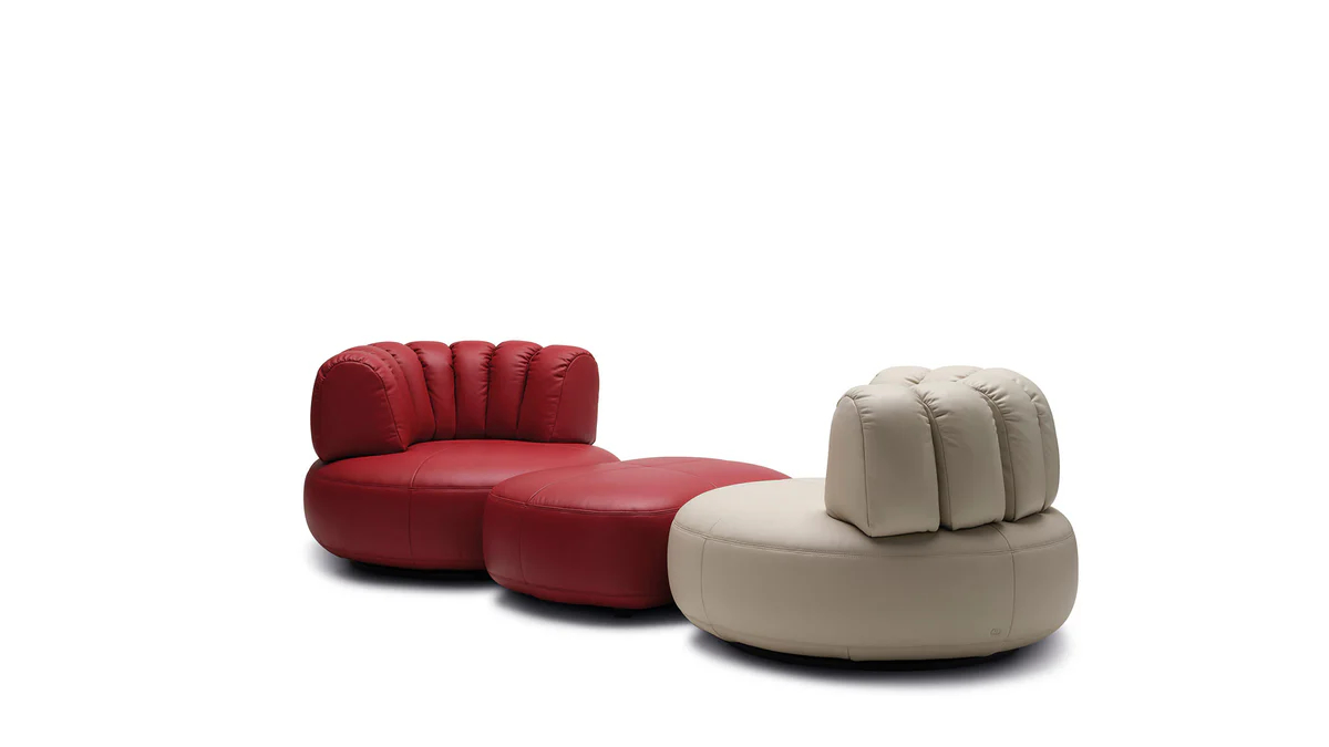 Upholstered lounge chair with circular base and segmented padded backrest, soft sculptural design.