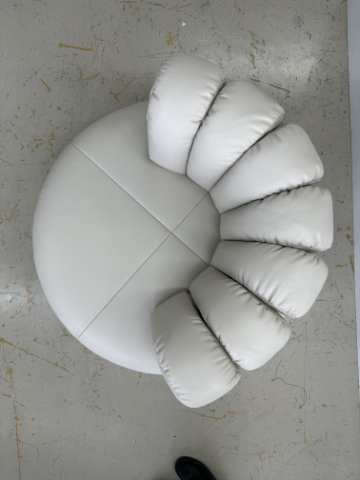 Upholstered lounge chair with circular base and segmented padded backrest, soft sculptural design.